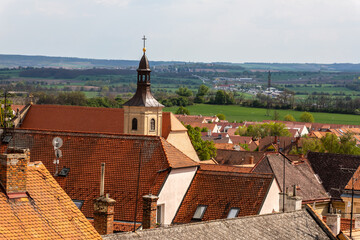 Scenic rooftop view of Mikulov with church tower and countryside. A picturesque view over the red-tiled rooftops of Mikulov, Czech Republic, featuring a historic church tower with rolling green fields
