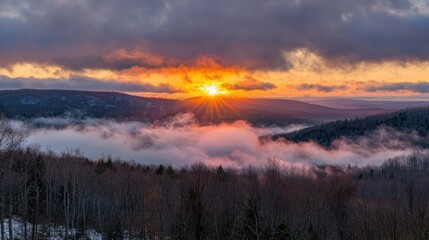 Obraz premium A sunrise breaking through thick clouds over a mountain range.