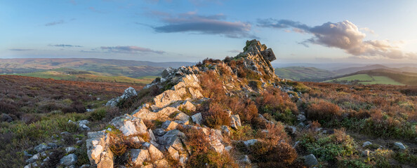 Panoramic landscape image of sunset colours at a rock formation on the Stiperstones National Nature...