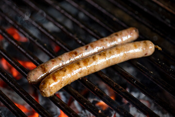 Grilling sausages on the grill with flames and smoke.