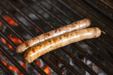 Grilling sausages on the grill with flames and smoke.