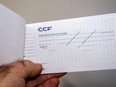 Paris, France - Dec 20, 2024: A person holds an open CCF bank checkbook featuring printed account details, bank contact information, and designated fields for amount and payee.
