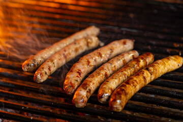 Grilling sausages on the grill with flames and smoke.