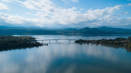 Aerial view of a bridge spanning a wide river, connecting two lush green landscapes.