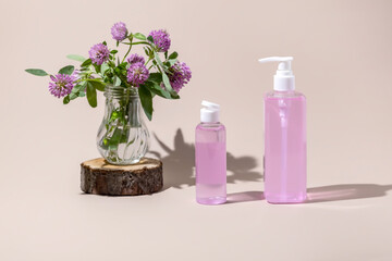 skin care products and red clover flowers on a beige background