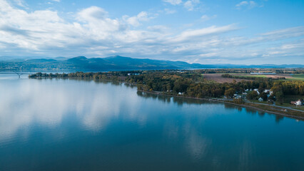 Aerial view of a bridge spanning a wide river, connecting two lush green landscapes.