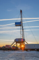 Fototapeta premium Industrial winter landscape featuring an operational drilling rig with support facilities at a remote worksite during daylight hours