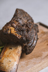 roasted veal rib with baked potatoes and vegetables on a wooden board