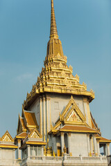 Majestic Golden-Spired Temple with Intricate Thai Architectural Details, Featuring Ornate Roofs and Marble Facades, Set Against a Clear Blue Sky in Bangkok, Thailand, Symbolizing Buddhist Spirituality