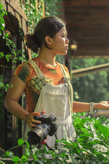 young asian Woman Photographer with Camera in a Lush Garden, Casual Outdoor Setting