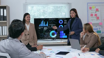 Professional businesswomen reviewing data, sharing statistical insights during collaborative strategy meeting in contemporary corporate workspace - Powered by Adobe