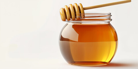 Fresh honey in a glass jar with a wooden dipper displayed on a clean surface