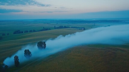 Fototapeta premium Aerial view of fog rolling through a field at dawn.