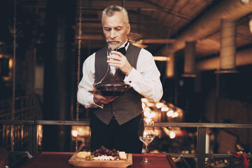 Experienced elegant sommelier tasting wine, inhaling vapors from decanter and wine. Wine tasting.