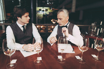 Confident elegant sommelier makes wine list in restaurant. Wine tasting.