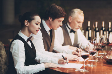 Group of sommeliers make wine card in restaurant. Tasting of elite alcoholic beverages.