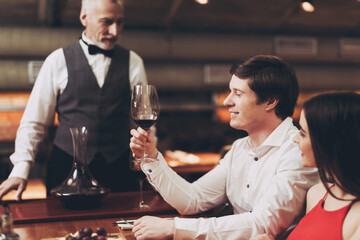 Young happy man is holding glass of wine. Sommelier recommends wine for couple.