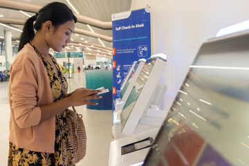 Young woman using self check-in kiosks in airport terminal.