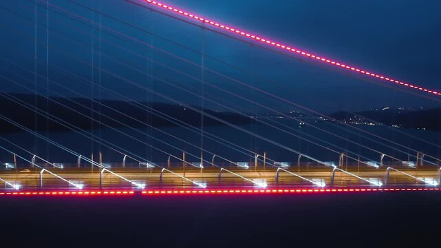 Yavuz Sultan Selim Bridge in Istanbul at dawn, with red lights illuminating the structure and vehicle lights creating dynamic trails, set against a dark blue sky and distant city lights
