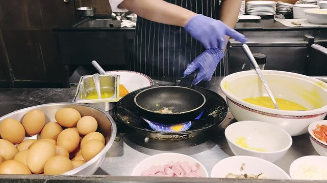 A hotel chef prepares a fresh omelet over an open flame. A delicious breakfast dish made with eggs, ham, and vegetables, cooked to perfection in a busy kitchen.