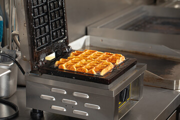 Cooking belgian waffles in the waffle iron in cafe kitchen