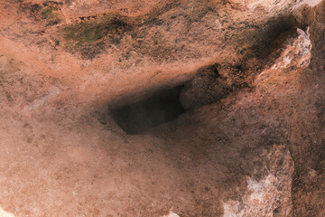 Mysterious dark hole in the earthy ground.  Intriguing texture and earthy tones create a sense of depth and mystery. Perfect for backgrounds, textures, or abstract designs.