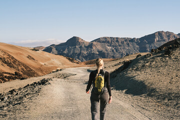 A lone hiker walks a scenic mountain path, enjoying breathtaking views of volcanic landscape.  Perfect for travel, adventure, and outdoor lifestyle projects.Tenerife