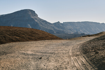 Stunning desert landscape with a gravel road leading towards majestic mountains under a clear sky. Ideal for travel, adventure, and nature themes.