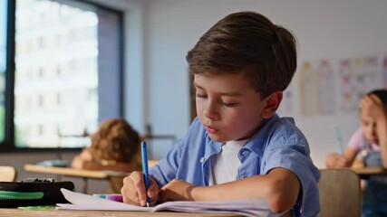 Smart schoolboy listening teacher making notes in copybook closeup. Cute boy