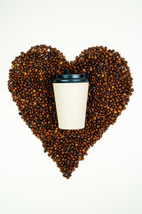 Naklejka premium Paper mug with coffee stands on coffee beans. Heart made of coffee beans