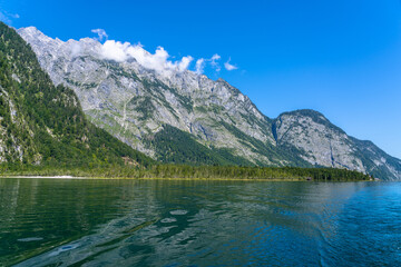 Fototapeta premium Beautiful panorama view of Konigssee Lake with peak Watzmann and Bavarian alps in background in Berchtesgaden national park on a sunny summer day with blue sky and cloud, Schoenau, Bavaria, Germany