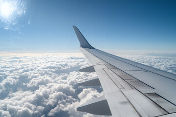 Obraz premium Airplane wing soars above clouds in the blue sky
