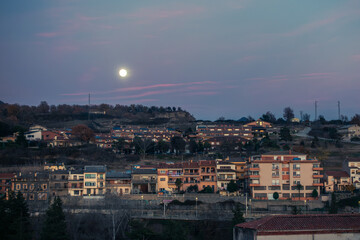 Village under a cloudy sky with a full moon