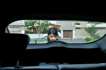 A teenager is looking out the window of a car