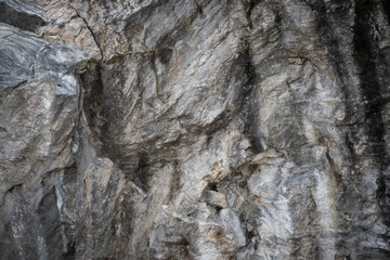 A rocky mountainside with white trails and depressions washed out by rain