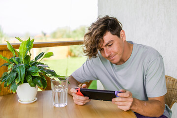 Man watching a game console in a terrace in summer. Technology and game addiction concept