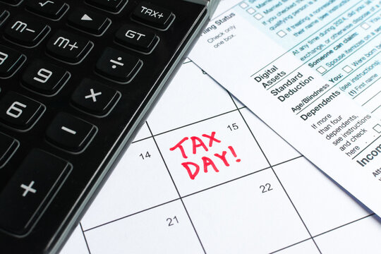 Close up shot of a calendar, with Tax Day reminder on the 15th, deadline for submission. With a calculator and Form 1040 U.S. Individual Income Tax Return. Taxation, tax season, reminder, extension