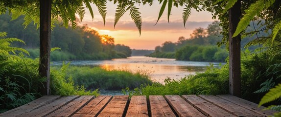 Obraz premium Lush greenery frames a wooden platform at sunset near a tranquil river in a serene natural setting