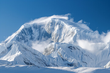 A breathtaking snow-covered mountain rising majestically against a crystal-clear blue sky, its towering white peaks glistening under the golden sunlight