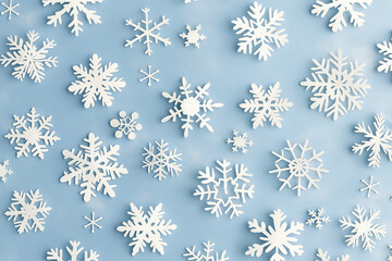 A delicate and elegant seamless background featuring abstract hand-drawn white snowflakes scattered across a soft blue backdrop 