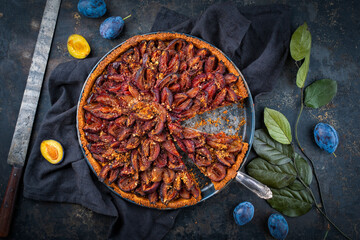 Traditional German Zwetschgenkuchen with sliced plums offered as top view on a rustic backing sheet