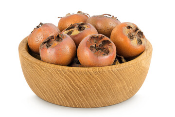 Brown fresh medlars in wooden bowl isolated on white background. Mespilus germanica close-up