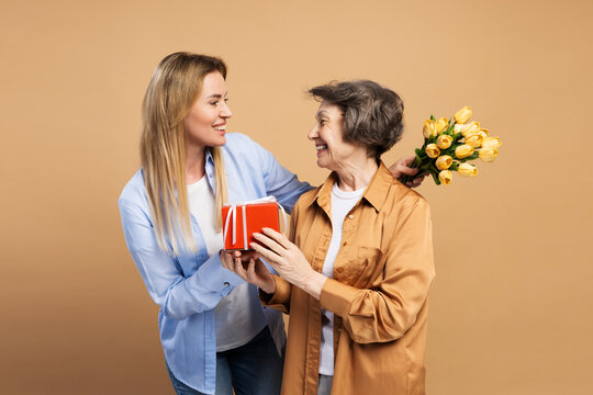 Daughter giving mother flowers and gift for mother's day