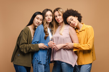 Four young women embracing diversity and friendship on beige background