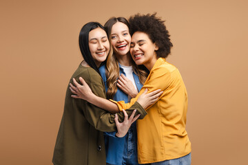 Three happy female friends hugging each other, embracing diversity and friendship