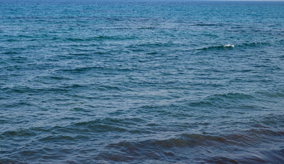 Calm blue waters gently ripple under the soft light of the early afternoon sun