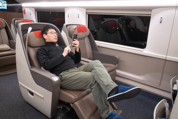 asian man using smart phone in high speed train in china