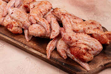 Chicken wings, marinated and laid out on a wooden platter, ready for cooking, grilling or baking, in a home kitchen, there are no people