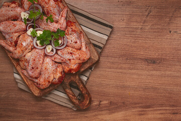 Chicken wings, marinated and laid out on a wooden platter, ready for cooking, grilling or baking, in a home kitchen, there are no people