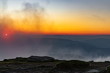 Fototapeta premium orange sky after sunset, view from the top of Mount Petros, clouds swirling around